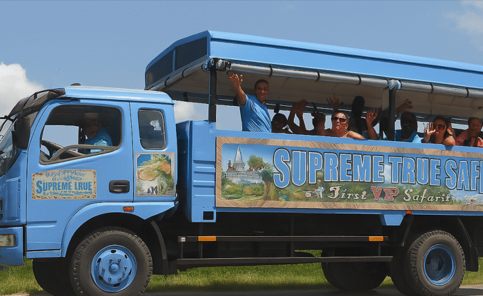 Guests enjoying the open-air ride on the Supreme True Safari truck through the Dominican countryside, smiling and waving under sunny skies
