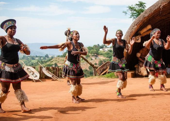 Visitors walking toward the Mandela sculpture at the Capture Site, with Zulu dancers performing at PheZulu Cultural Village and mist rising from Howick Falls