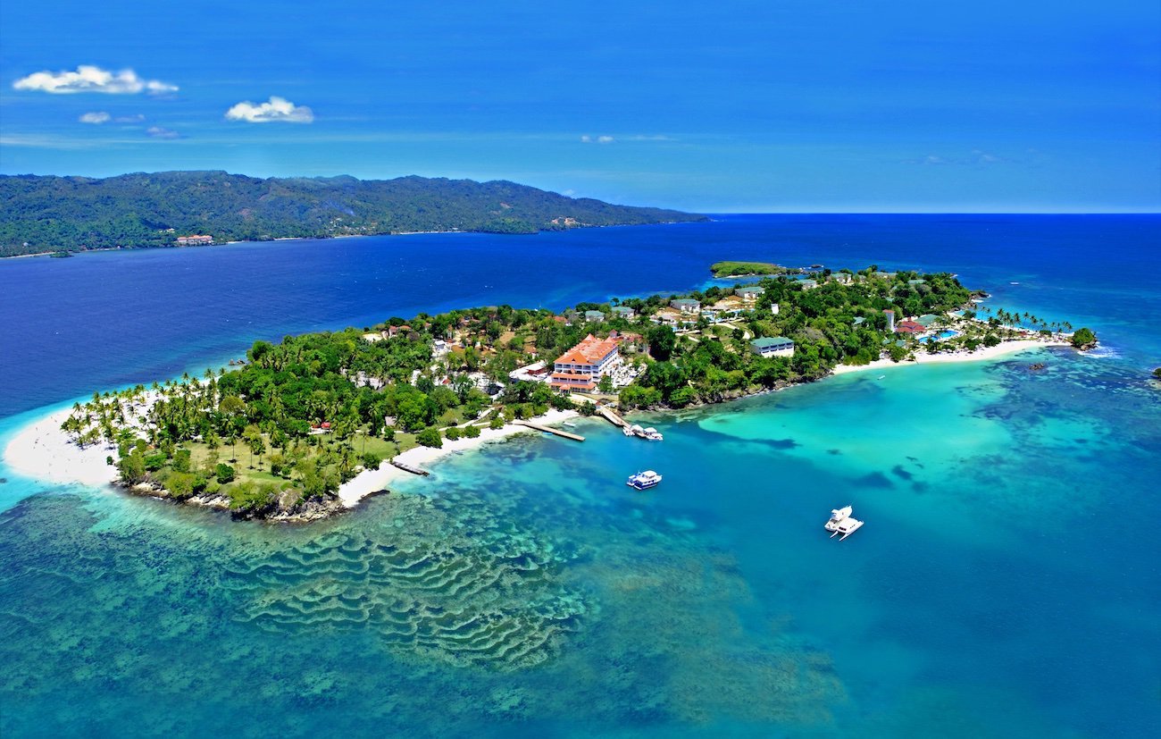 Samana Bay waterfront with sailboats and turquoise water.