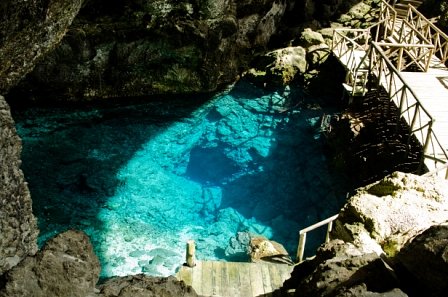 Agua cristalina del cenote rodeada por paredes rocosas.
